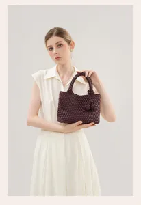 Close-up detail of the dark burgundy woven leather handbag featuring unique knotted handle.