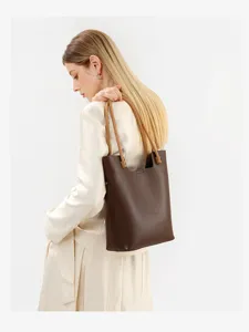Detailed shot of a vintage brown leather tote bag with thin double handles on model.