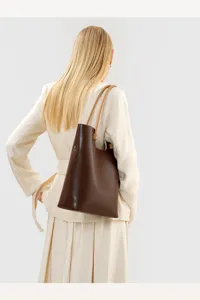 Detail view of a vintage dark brown leather tote shoulder bag worn on shoulder by a model.