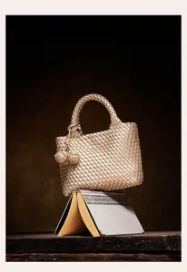 Exquisite gold woven handbag detail, artisanal intrecciato texture with chic knotted charm.