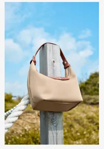 Outdoor detail shot of the nylon lunch handbag featuring a leather handle and classic shape.