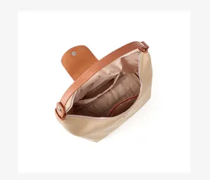 Classic nylon dumpling shoulder bag with brown leather flap, spacious interior compartment.
