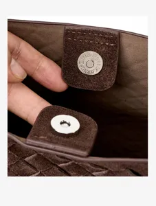 Close up of dark brown woven leather bag interior, highlighting magnetic snap button detail.