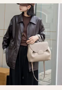 Detail shot of stylish commuter leather handbag in beige, premium texture and flap design.