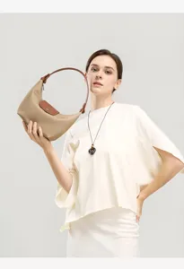 Close-up detail shot of a classic nylon handbag held by a model, featuring leather handle.