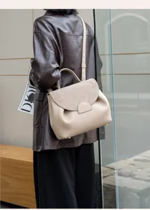 Detailed view of stylish beige leather handbag with suede flap, chic and elegant design.