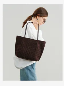 Detailed showcase of a brown woven leather shoulder tote bag carried by female model.