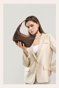 Brown nylon underarm bag detail showing leather flap handle and classic commuter shape.