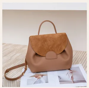 Close-up detail of brown leather and suede top-handle handbag, daily commute use.