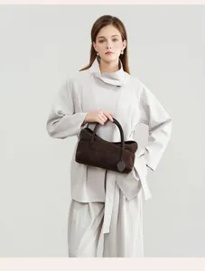 Detail shot of a vintage brown suede pillow handbag, chic commuter shoulder and crossbody bag.