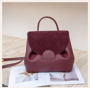 Wine red top layer cowhide handbag detail, stylish top handle and elegant suede flap design.