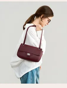 Close-up view of the wine red leather shoulder bag, stylish metal turn-lock and pebbled texture.