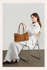 Detail view of brown suede tote bag styled in elegant lifestyle scene with female model.