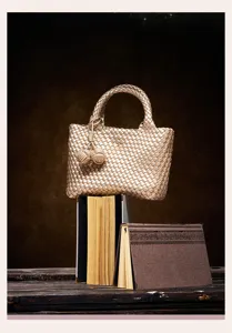 Detailed view of the metallic gold woven tote bag featuring elegant handle and double knot charms.