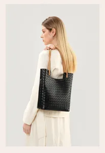Close-up view of the elegant black woven leather tote bag with comfortable light brown handles.