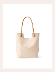 Beige woven leather tote bag detail showing intrecciato pattern and brown handles.
