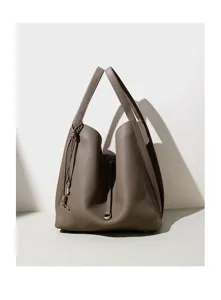 Close-up detail of the minimalist taupe leather bucket bag showing fine texture and sleek handles.