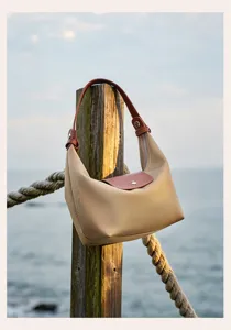 Detail view of the stylish khaki nylon shoulder bag hanging outdoors on a wooden post.