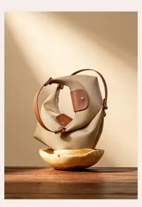 Detail view of stylish khaki nylon shoulder dumpling bag with brown leather flap trim.