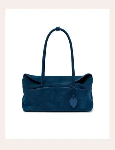 Close-up detail of dark blue suede shoulder bag, showing soft texture and long straps.