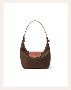 Detail view of brown nylon shoulder bag with leather flap handle compact hobo design