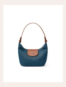 Detailed view of the blue nylon shoulder bag with brown leather flap and elegant handle style.