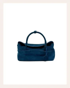 Detailed view of the dark blue suede pillow handbag featuring smooth texture and elegant top handle.