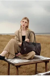 Detailed shot of a minimalist brown leather tote bag in a vintage outdoor scene setting.