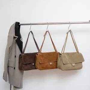Detailansicht der lässigen Wildleder-Umhängetaschen an einer Metallstange, sehr stilvoll.