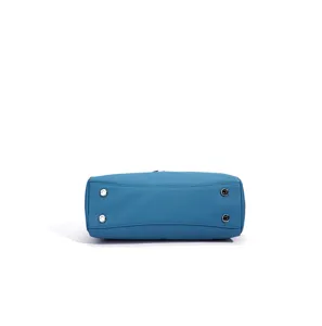Close-up detail of the bottom of a blue leather shoulder bag with metal feet, elegant and durable.