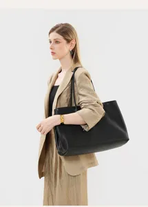 Detail view of the black leather tote bag worn on shoulder, highlighting texture and capacity.
