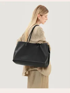 Detailed view of women's black leather tote bag, elegant underarm style, minimalist chic.