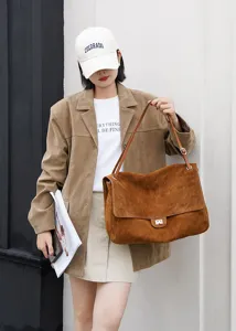 Detailaufnahme der braunen Wildleder-Schultertasche mit Metallverschluss und grossem Volumen.