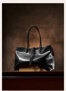 Detail shot of minimalist black leather tote bag with double straps and vintage textured finish.
