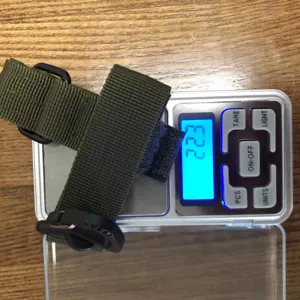 Vista di dettaglio del cinturino tattico in nylon per guanti pesato su bilancia digitale.
