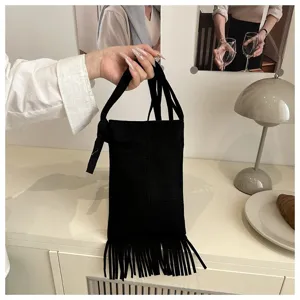 Detalle de bolso cruzado para teléfono con flecos negros estilo bohemio vintage con borlas.
