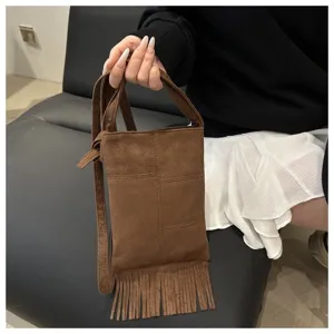 Detalle de bolso bandolera de ante marrón con flecos, mostrando su textura y diseño chic.