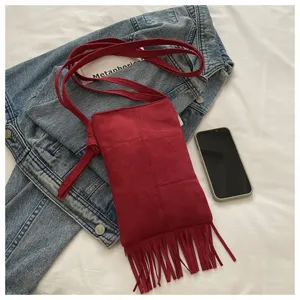 Primer plano del detalle del bolso cruzado de ante rojo con flecos, estilo bohemio.