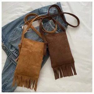 Vista detallada de bolsos cruzados de ante sintético con flecos boho en tonos marrones.
