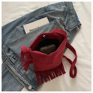 Vista detallada del bolso cruzado con flecos bohemios rojos, material suave y bolsillo.