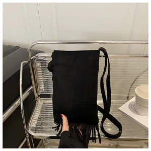 Detalle de bolso cruzado negro con flecos, elegante bolso de ante con borlas para mujer.