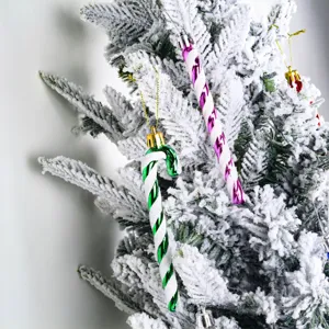 Close-up detail of glittering plastic candy cane ornaments hanging on a snowy Christmas tree.