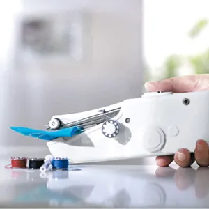 Detail shot of portable mini electric handheld sewing machine in use with thread spools.
