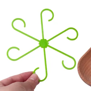 Vue detaillee du support de plante en plastique vert a 6 crochets et etagere de rangement.