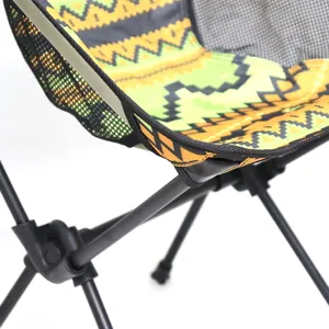 Close-up detail of outdoor folding camping moon chair with colorful ethnic geometric print fabric.