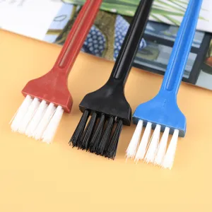 Close-up detail view of three colorful plastic cleaning brushes designed for tiny keyboard gaps.