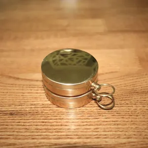 Detailed view of the vintage brass pocket compass showcasing metallic cover and ring.
