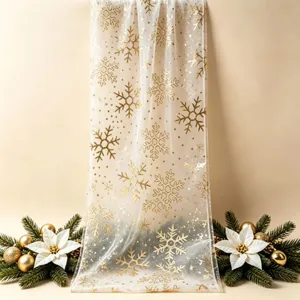 Camino de mesa transparente con copos de nieve dorados y tela decorativa navideña.