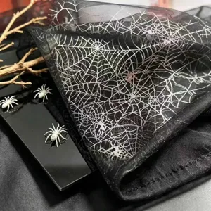 Primo piano di runner da tavolo in pizzo nero con ricamo di ragnatela argentata per decorazione.