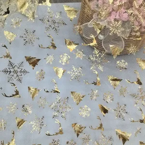 Tela de malla estampada con lámina de oro con motivos de árboles de navidad y copos de nieve.